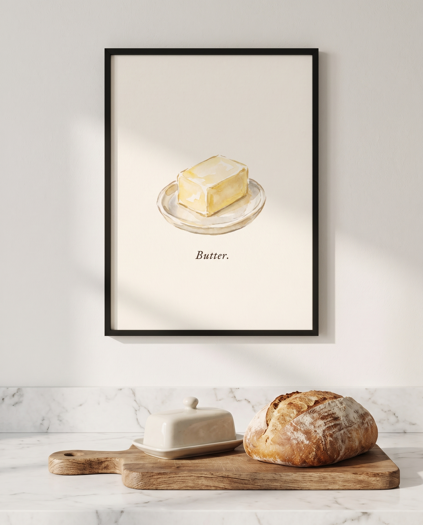 Butter kitchen print framed in black above a marble worktop